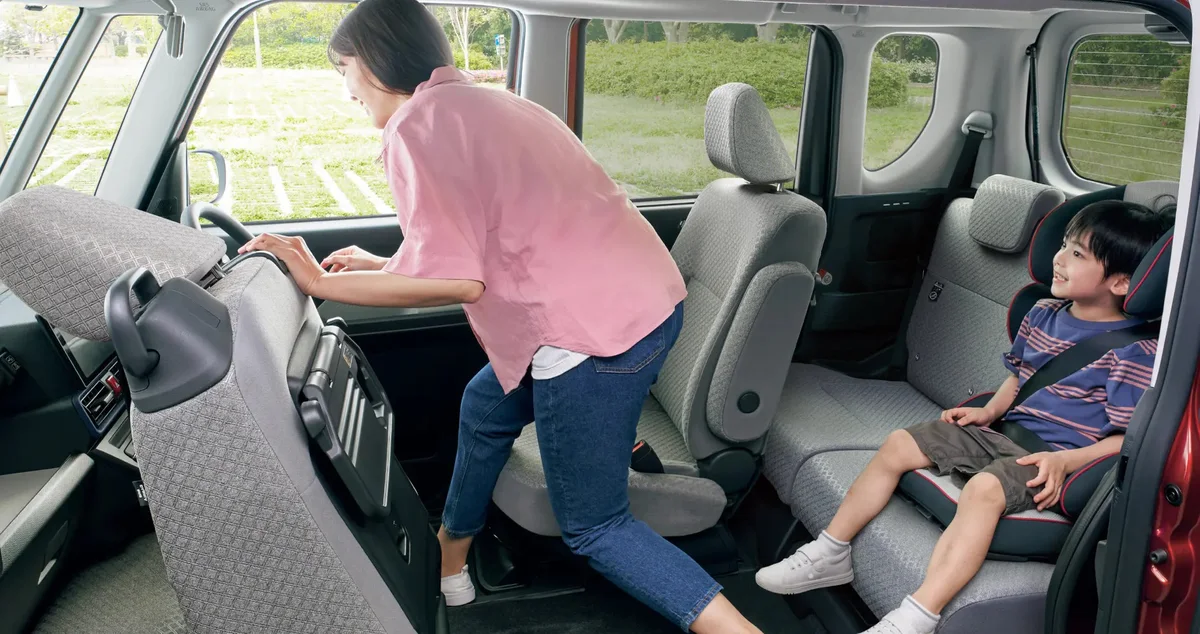 ダイハツ タント 運転席ロングスライドシートを使って後席のお子さまのお世話をする様子です（タント X 2WD、運転席ロングスライドシートはメーカーオプション）。
